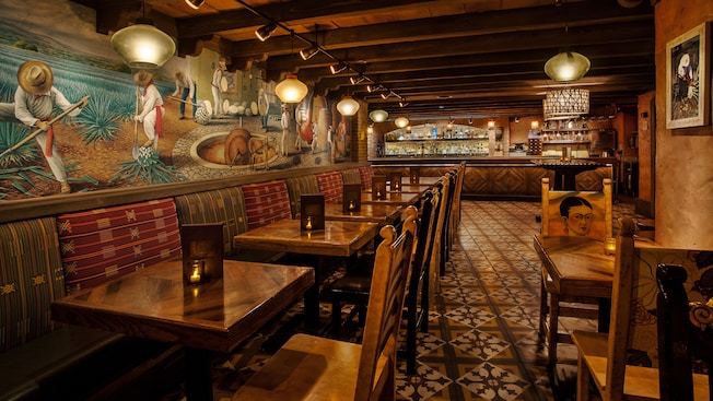Dining tables, chairs, beamed ceiling and Mexican mural on the wall