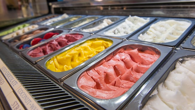 A display case features cold silver containers filled with various ice cream and sorbet flavors