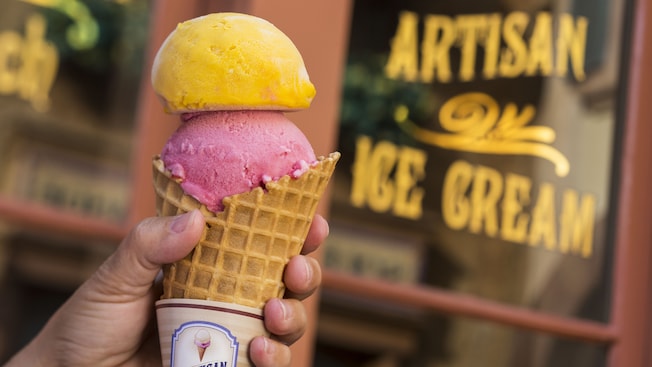 A waffle cone filled with two scoops of sorbet, outside of the front window of L'Artisan des Glaces