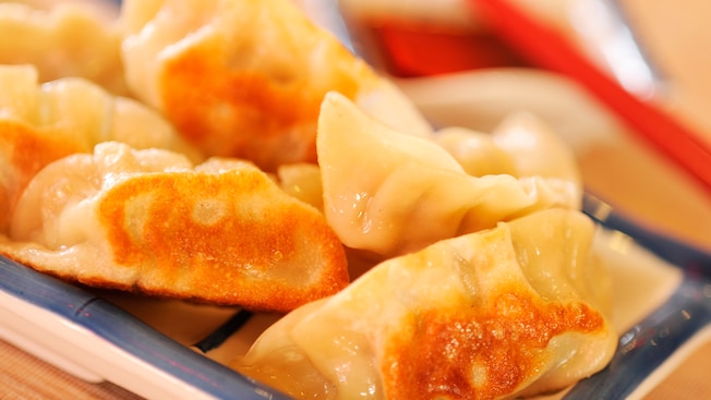 A selection of savory pot stickers which have been pan-fried to a crisp and served on a small plate