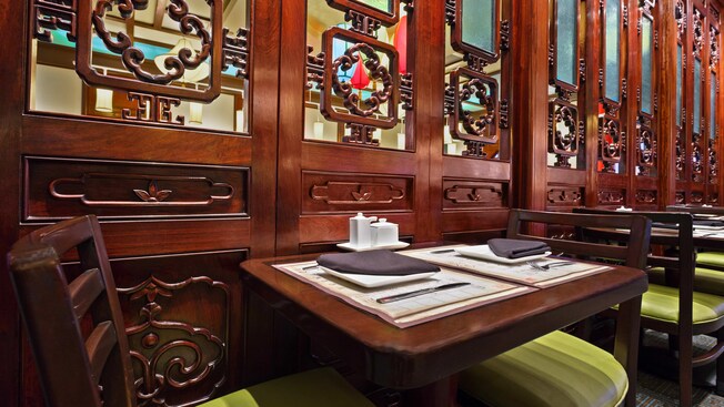 Table for 2 beside lacquered wood panels with decorative cutouts