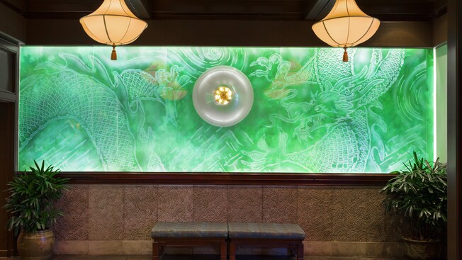 Green etched-glass mural of 2 dragons chasing a glowing pearl