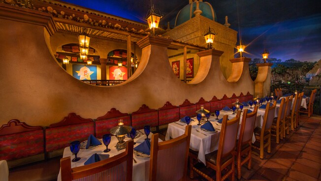 A 17th century-inspired hacienda, lit with lanterns and tables against wall