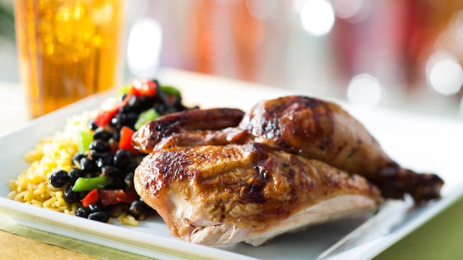 Roasted chicken on a plate with black beans and yellow rice