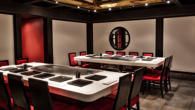 Two tables in front of a small round window in a Japanese-style dining area