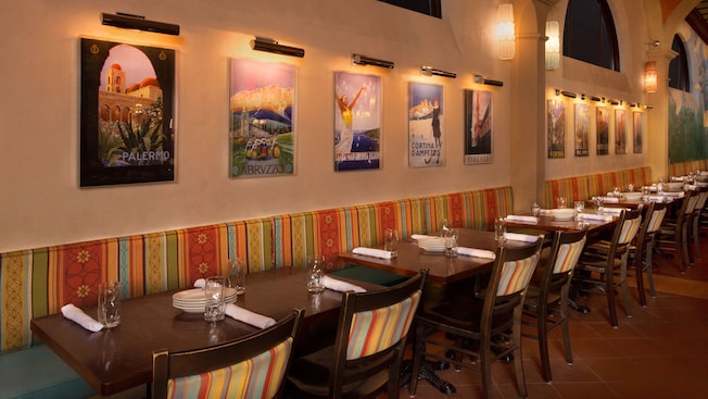 Lit travel posters on a dining-room wall above banquette seating