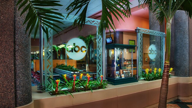 Recibidor y área de comidas divididos por una maceta y 2 particiones en vidrio tallado con el logotipo de ABC