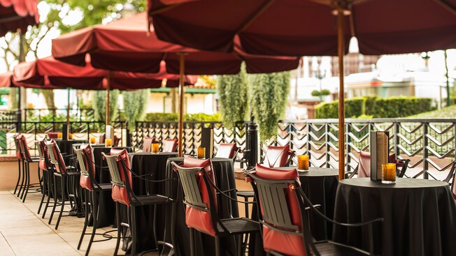 A row of cocktail tables with Art Deco chairs and umbrellas