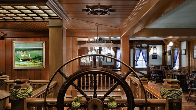 Frontal close-up of a ship wheel and sailor's knots in the wood-paneled dining room 