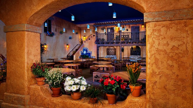 View of Southwestern dining area through an arched window with flower pots on its ledge