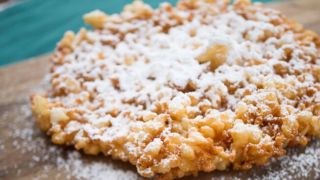 A close-up of a funnel cake dusted with powdered sugar