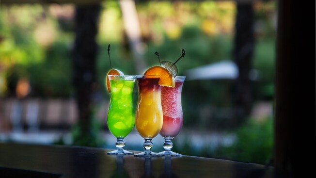 Three specialty drinks sitting on a wooden bar