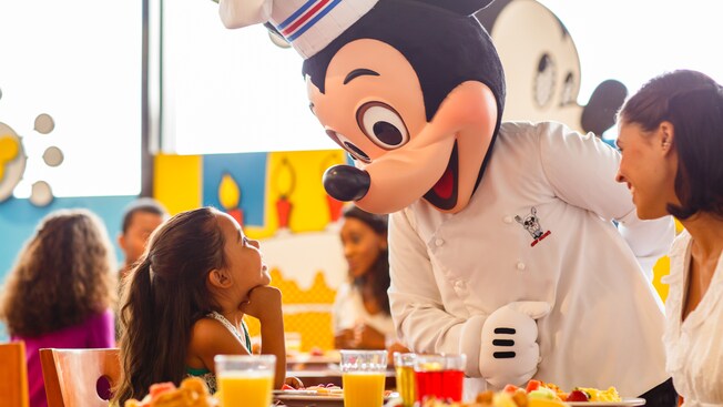 Chef Mickey greets a little girl and her mother at their breakfast table