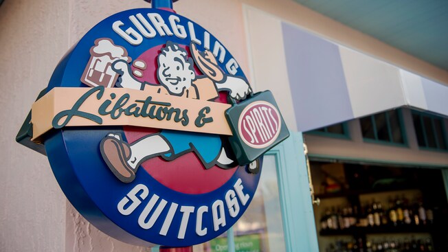 An exterior sign featuring Gurgling Suitcase Libations & Spirits at Disney Old Key West Resort