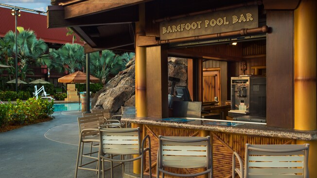 Patio area with chairs and Barefoot Pool Bar sign, with pool in the background