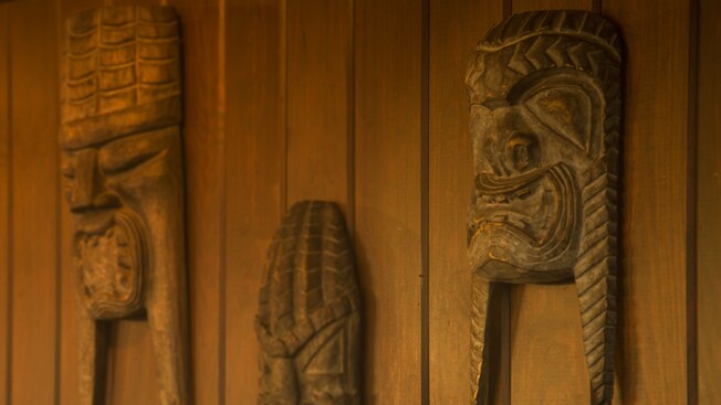 3 tiki sculptures hanging on a wall