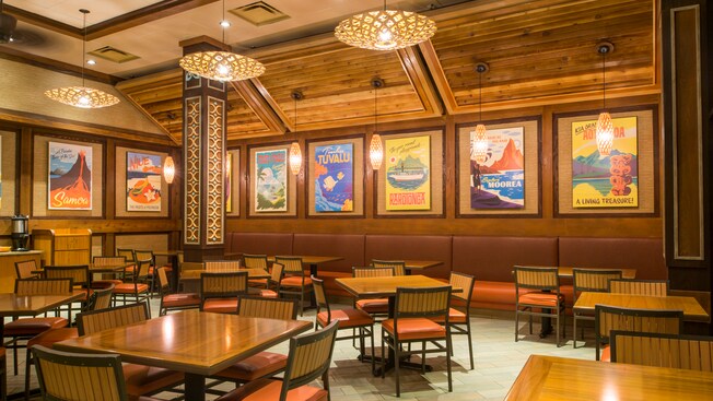 Dining area of Capt. Cook’s restaurant, with tables, chairs and retro island posters on wall