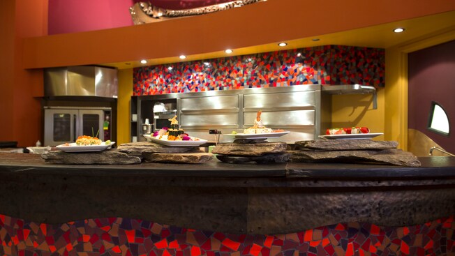 Platos de sushi habilidosamente preparados por el chef en el momento, sobre el mostrador de piedra y mosaicos de Kona Café