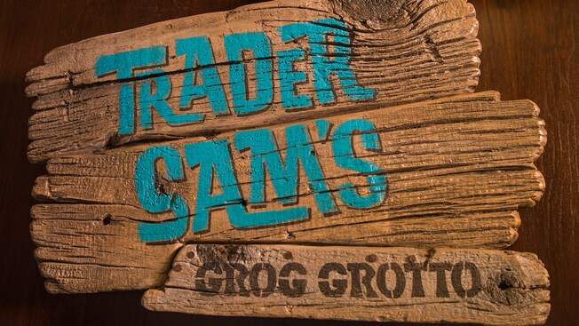 Rough-hewn wooden sign with painted name of tiki bar, Trader Sam’s Grog Grotto