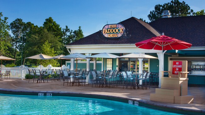 View of The Paddock Grill, patio tables and lifeguard chair from across the Paddock Pool