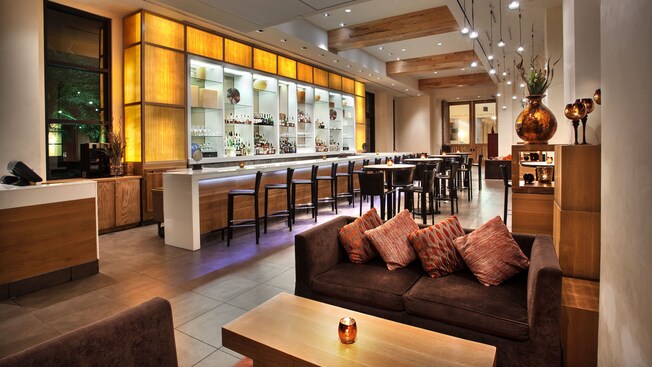 Sofá con 4 almohadones y mesa de centro adyacente al área del bar