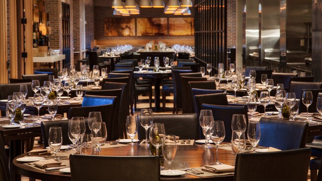 Long view of dining room, showing tables set with stemware and flatware