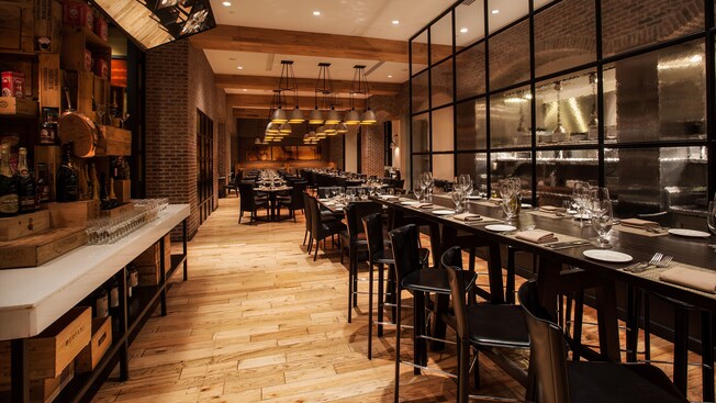 View of long bar-like counter and chairs opposite open kitchen