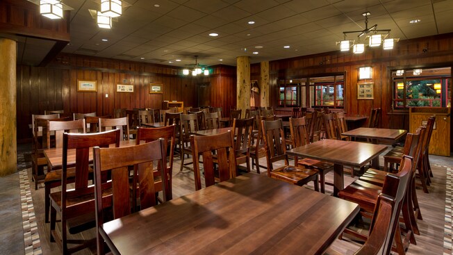 A restaurant dining room filled with several wooden tables and chairs