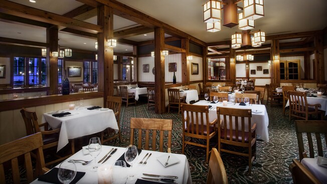 Dining area with wooden beams, carpeted floor and tables set for dinner
