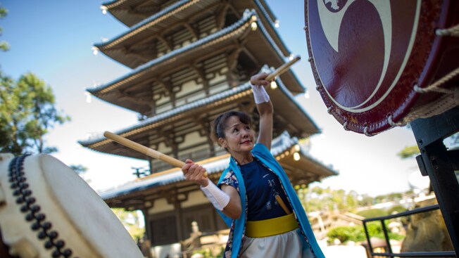 A female member of Matsuriza beats 2 Taiko drums in front of the Pagoda at Japan Pavilion