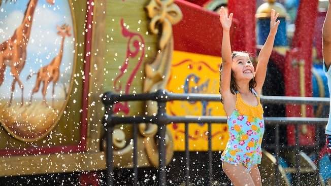 A little girl in a bathing suit delights while being splashed at Casey Jr. Splash 'N' Soak Station