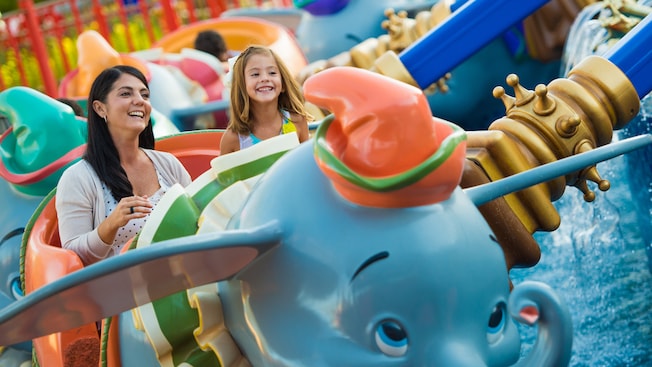 A mother and daughter gleefully ride in a Dumbo-looking car on Dumbo the Flying Elephant