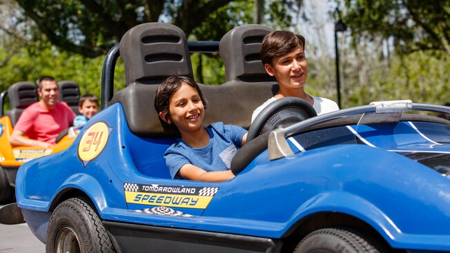 Two brothers drive in a car at Tomorrowland Speedway in Magic Kingdom park