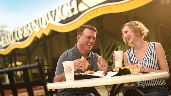 A couple sits at an outdoor table enjoying their Earl of Sandwich meals