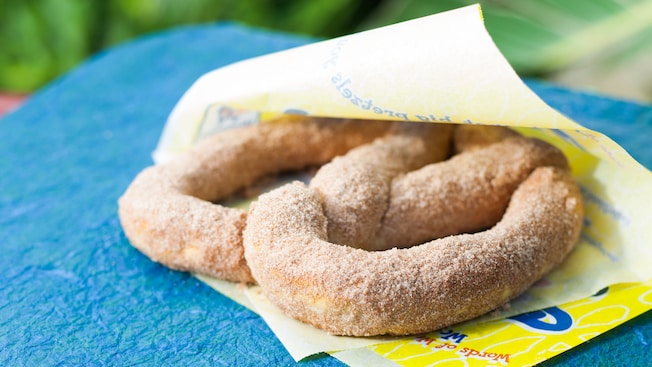 A large, doughy pretzel in a Wetzel's wrapper is covered in cinnamon and sugar