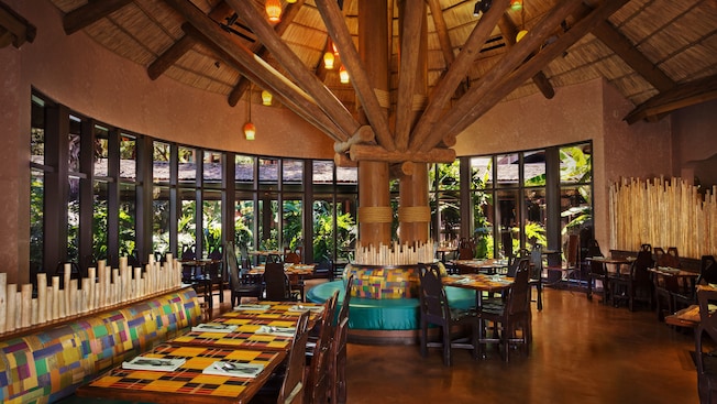 Dining area at Boma—Flavors of Africa, featuring a thatched ceiling and panoramic windows with a garden view