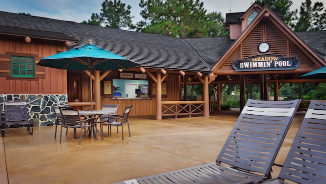 Chaises longues et table avec parasol sur un patio devant le Meadow Snack Bar