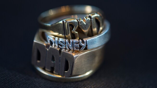 Una pila de anillos artesanales personalizados en exhibición en el puesto de Initial Rings en Disney Springs