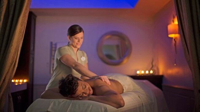 A masseuse kneads the shoulder muscles of a woman lying on a massage table
