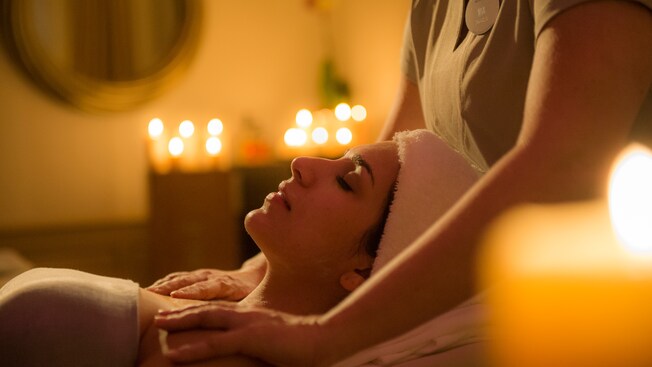 A female Guest with her eyes closed enjoys a massage from a masseuse