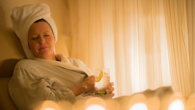 Woman in a robe with hair wrapped in a towel relaxes in a in a chiffon-curtained relaxation room