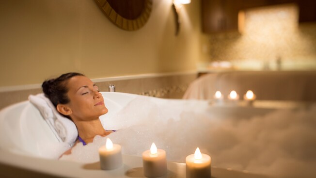 A female Guest luxuriates in a bathtub filled with bubbles