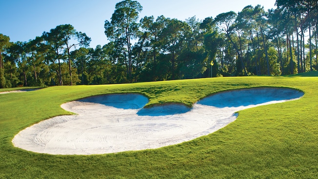 A sand trap shaped like the Mickey icon nearby a hole at Disney’s Magnolia Golf Course