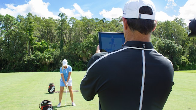 A golf instructor filming a Guest during a professional coaching session at Walt Disney World Resort