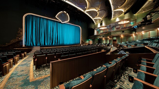 The Walt Disney Theatre on the Disney Wish cruise ship with ornate art deco ceiling details and rows of plush seating