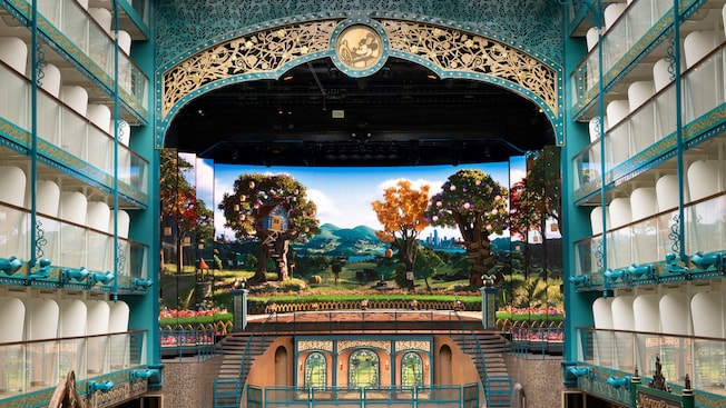 An expansive area with a tall theatrical stage, castle artwork and large lawn with amphitheater seating An expansive area with a tall theatrical stage, castle artwork and large lawn with amphitheater seating