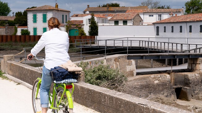 A woman pedaling a bicycle in a European countryside