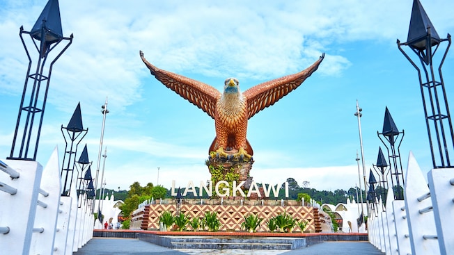 A large eagle statue with wings fully spread standing on a pedestal with a sign that reads ‘Langkawi’ A large eagle statue with wings fully spread standing on a pedestal with a sign that reads ‘Langkawi’