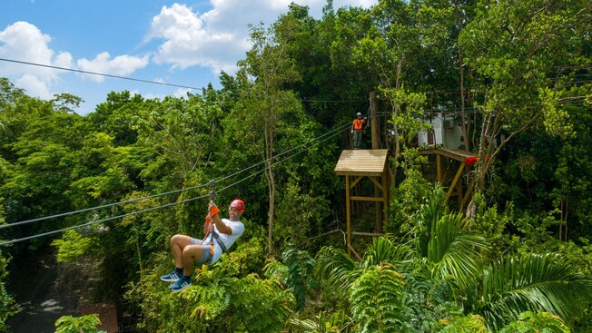 A Guest riding a zip line through a jungle