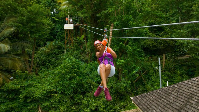 A woman riding a zip line through the jungle